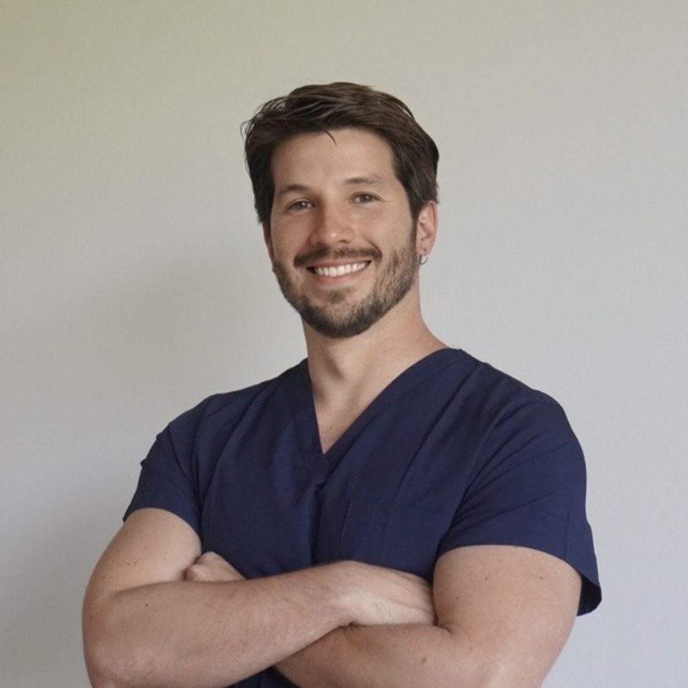 El Dr. David Sambrano sonriendo con los brazos cruzados, con uniforme azul marino